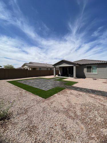 Paver patio bordered with artificial turf, viewed from the back corner of the yard