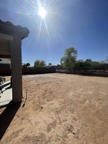 Dirt backyard before renovation looking out from beside the covered patio