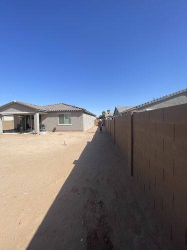 Side yard before renovation, bare dirt between the house and block wall