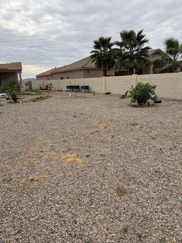 Wide gravel backyard before the build, nothing but rock wall to wall