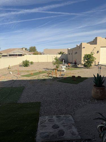 Loose turf remnants and gravel across the yard before the rebuild