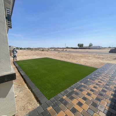 Artificial turf panel meeting the paver walkway and courtyard at a new build in Eloy