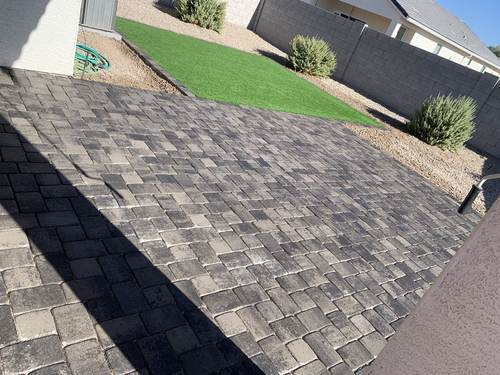 Paver walkway leading to an artificial turf backyard