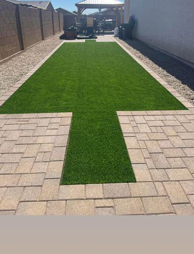 Side yard turf and paver walkway leading to a covered patio