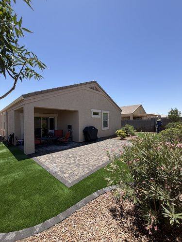 Paver patio with charcoal border beside the artificial turf lawn and flowering oleander