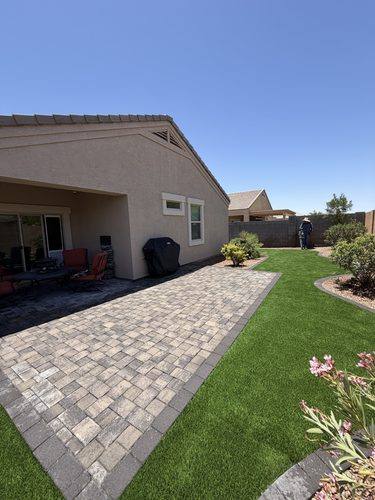 Completed paver patio and turf lawn seen from the side of the yard