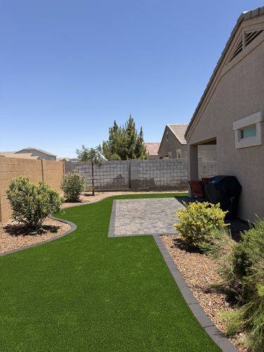 Wide view of the finished backyard with curved paver curbing and rock borders