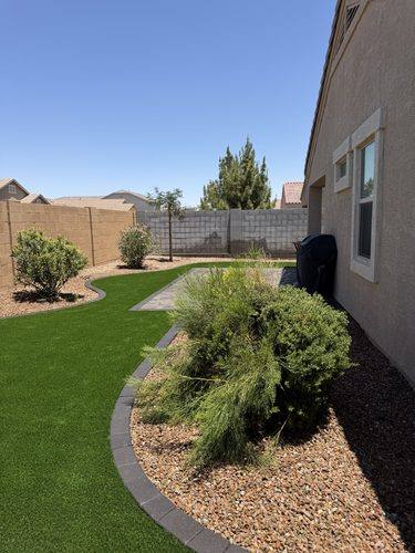 Curved turf lawn and rock planting beds running down the side yard
