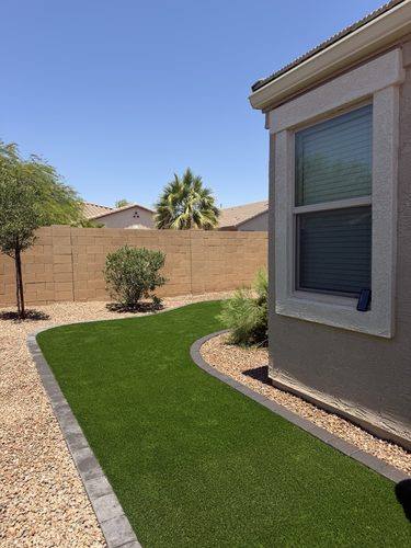 Artificial turf strip and paver curbing along the side of the house