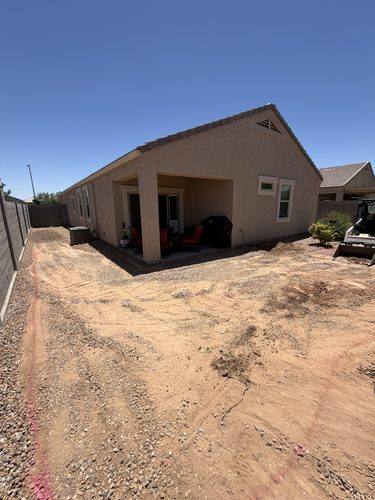 Bare dirt backyard before landscaping, with the new layout painted on the ground