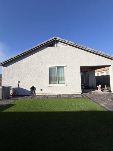 Rear of the house with a paver patio and artificial turf lawn