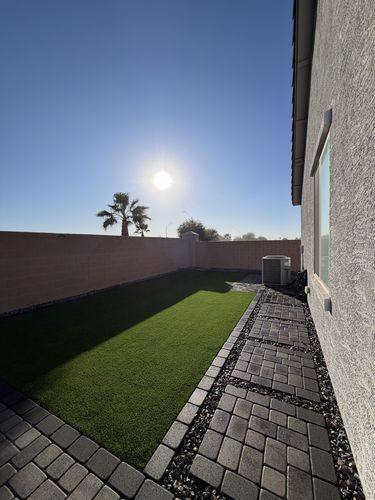 Paver walkway with decorative rock joints running beside the turf
