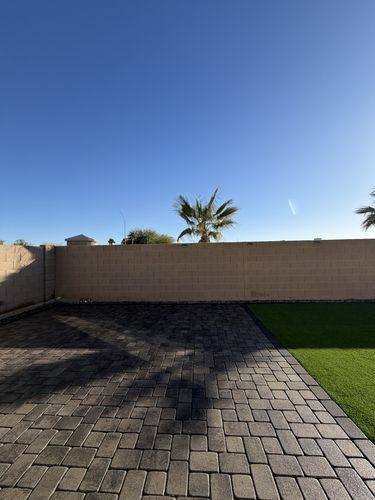 Paver patio meeting the turf lawn along the back block wall