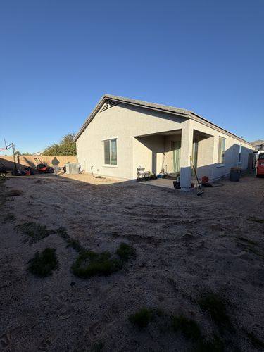 Bare dirt backyard before renovation, wide view of the rear of the house
