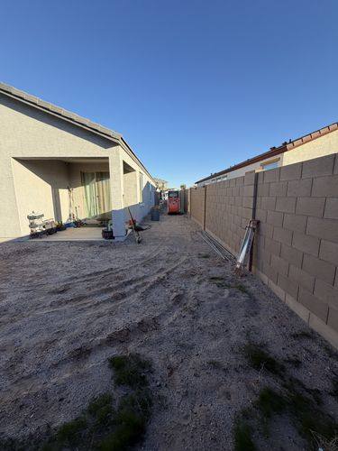 Graded dirt backyard during demo with a skid steer working