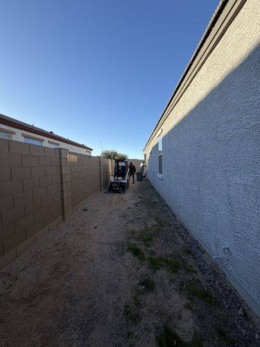 Narrow side yard of dirt and weeds before the paver walkway