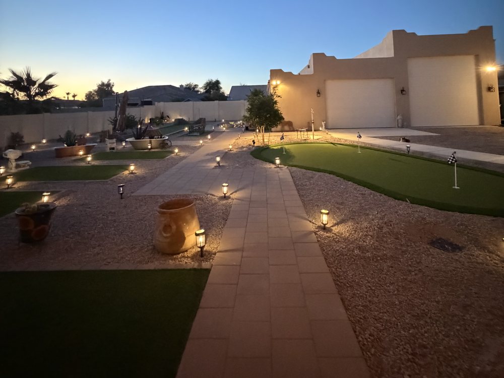 Finished Casa Grande backyard at dusk, with landscape lighting along the paver walkway and the putting green lit up