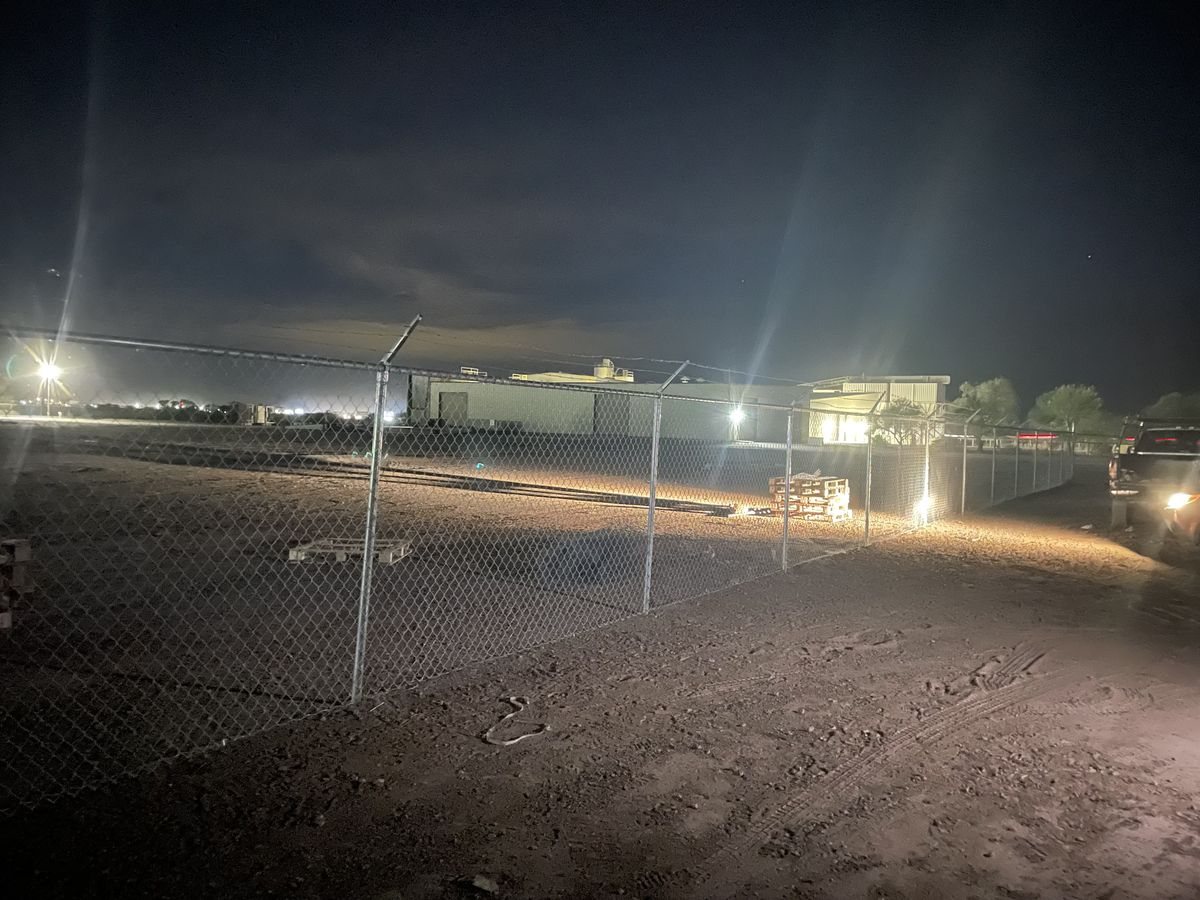 Galvanized commercial chain-link fence on a dirt lot in Eloy at night