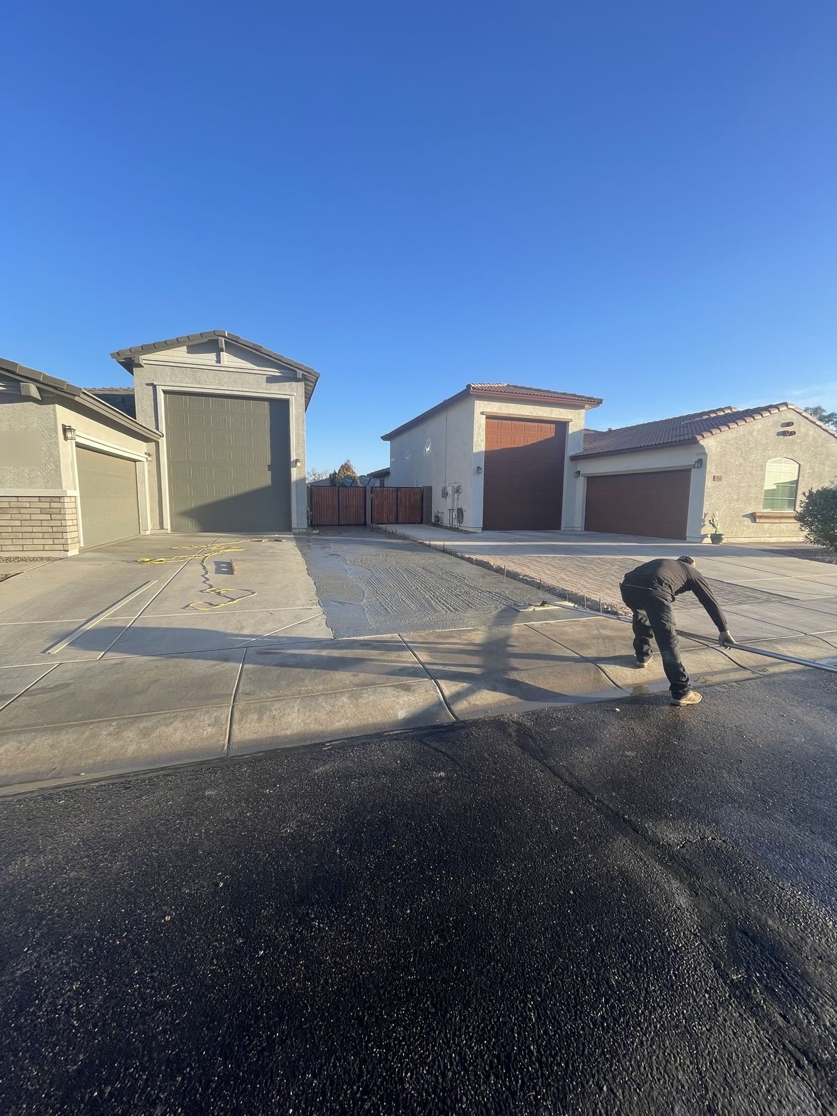 Crew member screeding a fresh concrete driveway extension pour at the curb