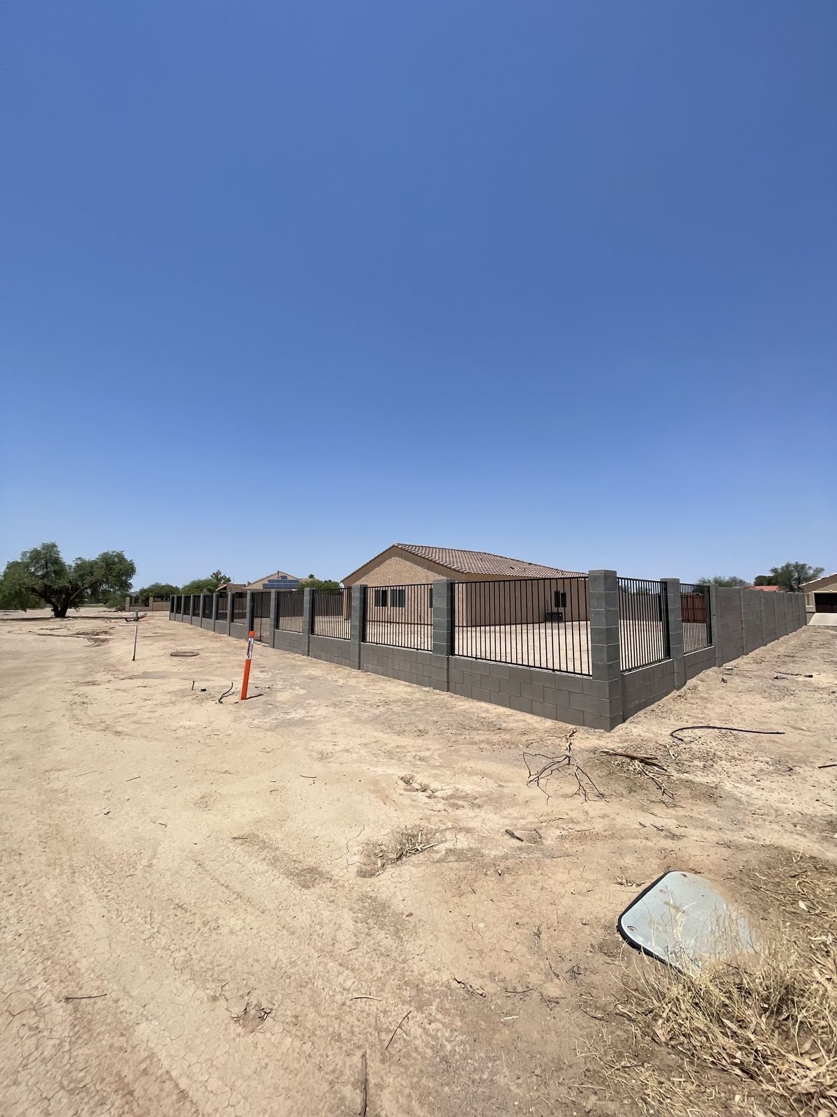 Block wall with wrought iron view fencing panels wrapping a corner lot in Arizona City
