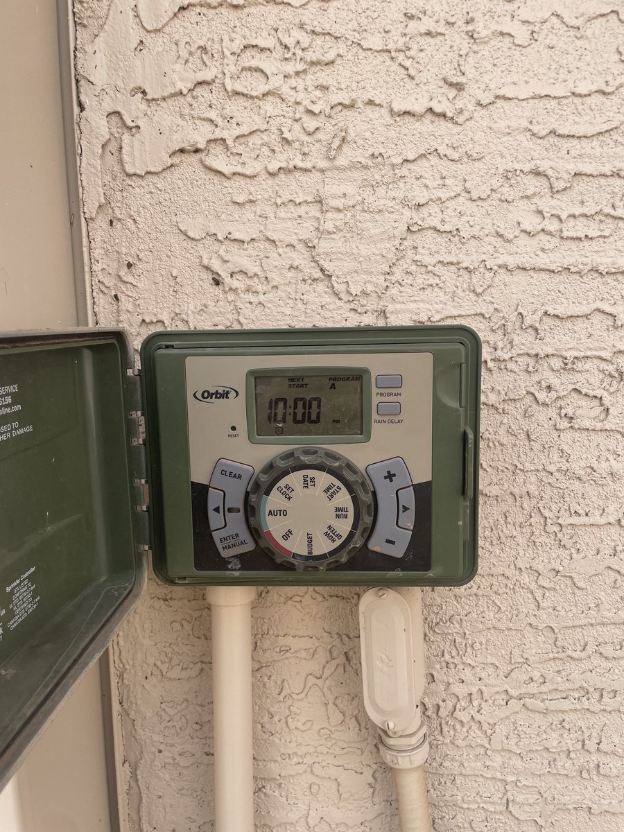 Irrigation controller mounted on a stucco wall, set to run at night