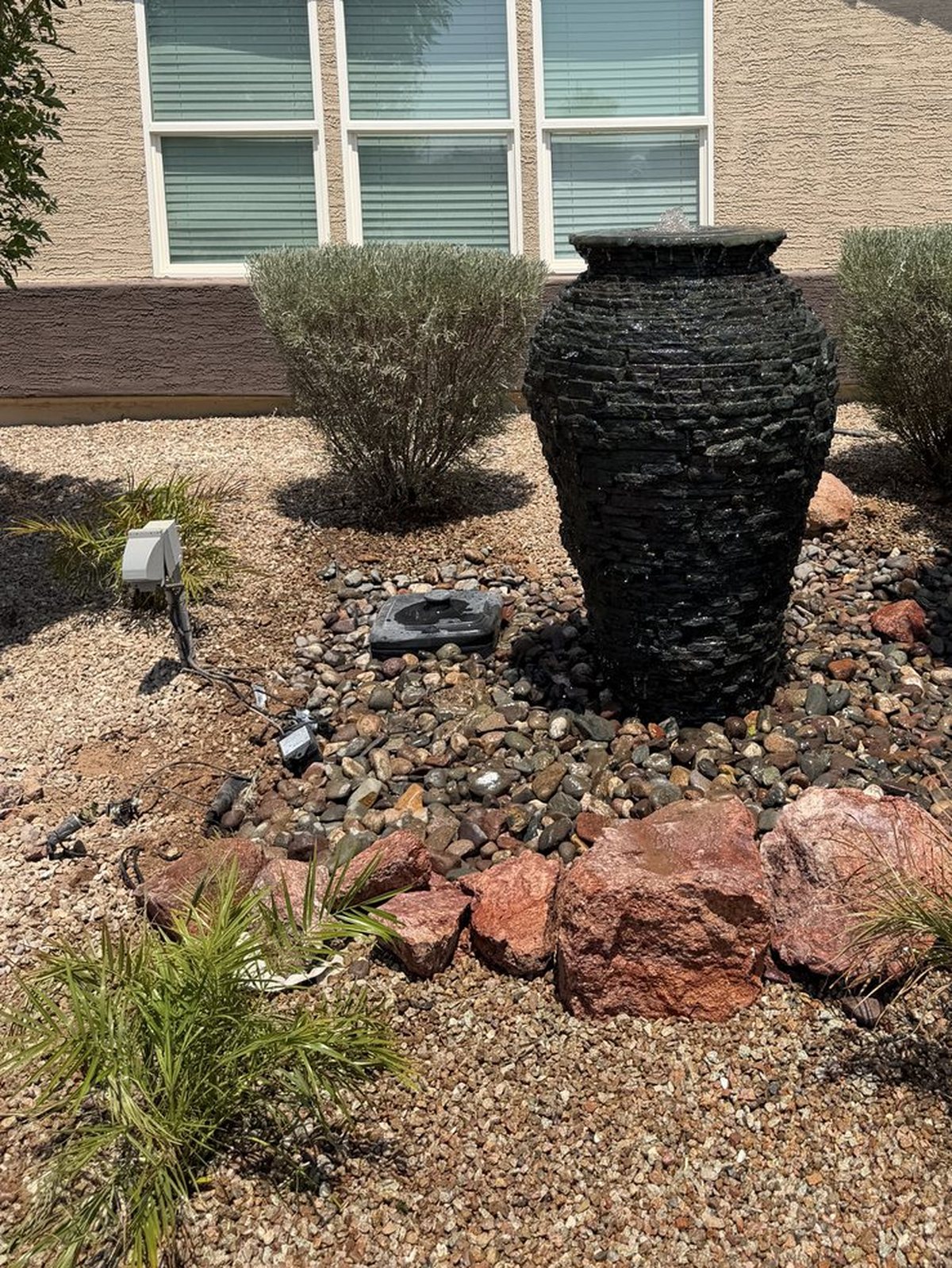 Stacked stone urn fountain set in river rock in a Casa Grande front yard