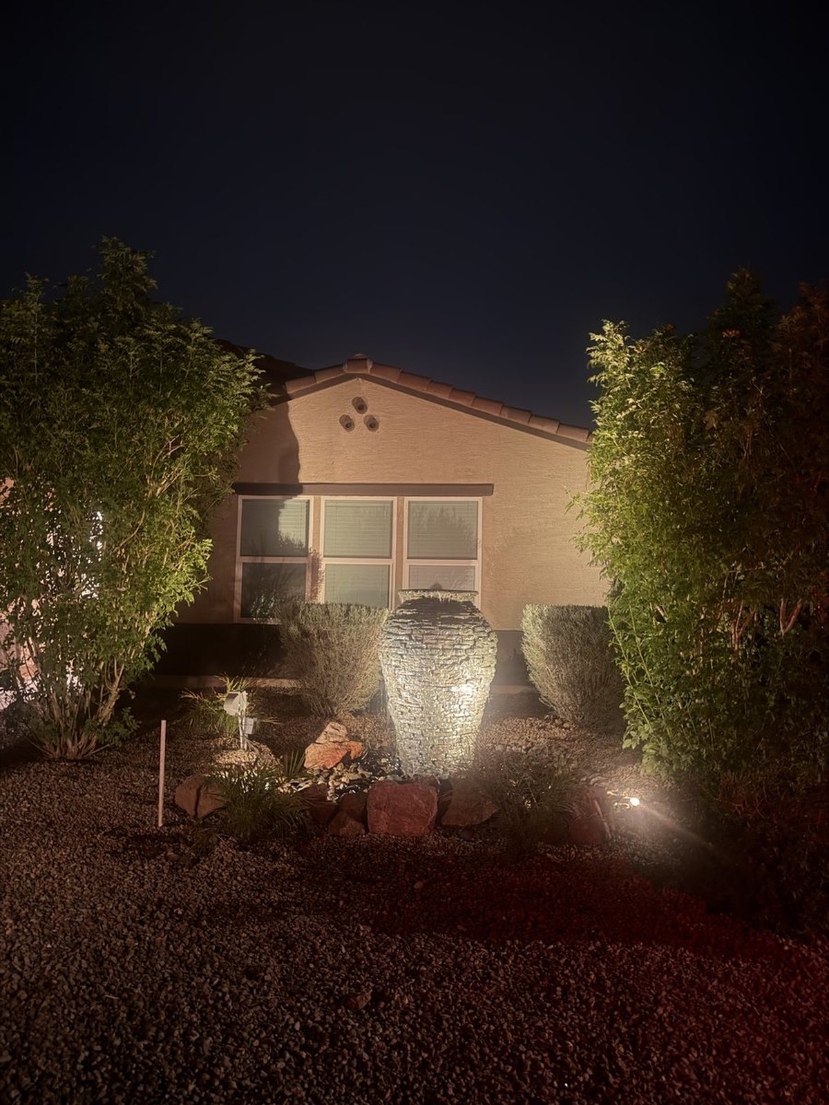 The same stacked stone urn fountain lit after dark