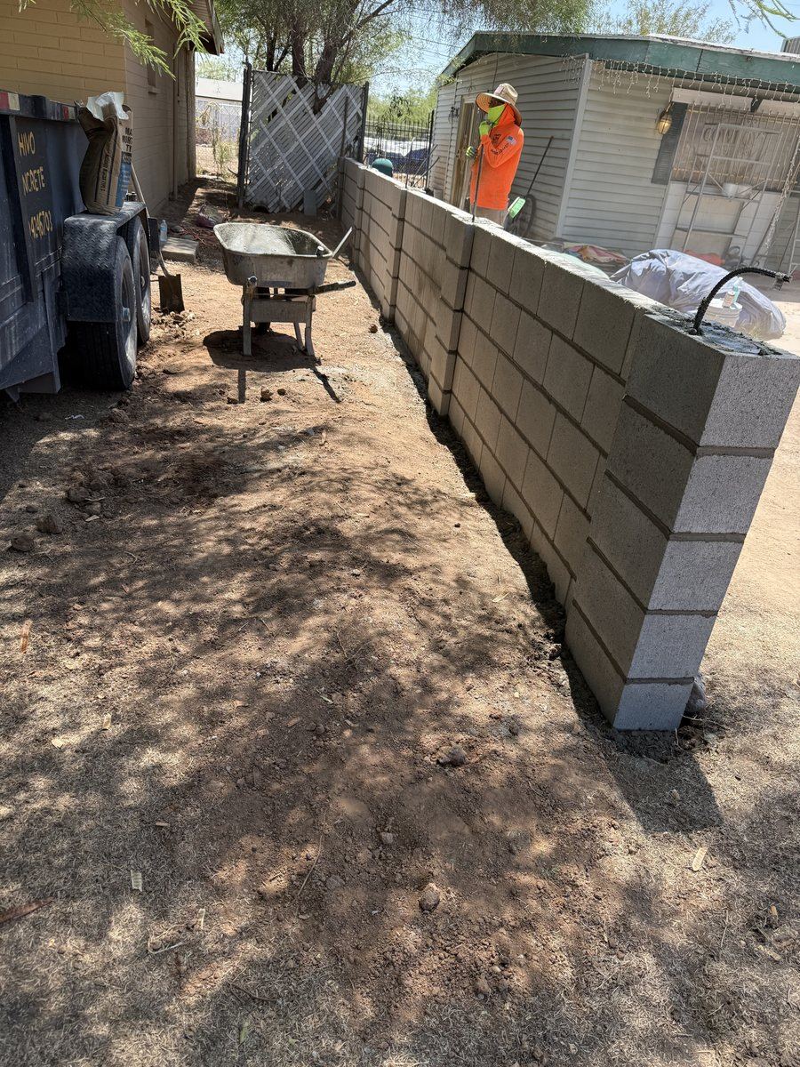 Mason building a CMU block wall with rebar and grout in progress