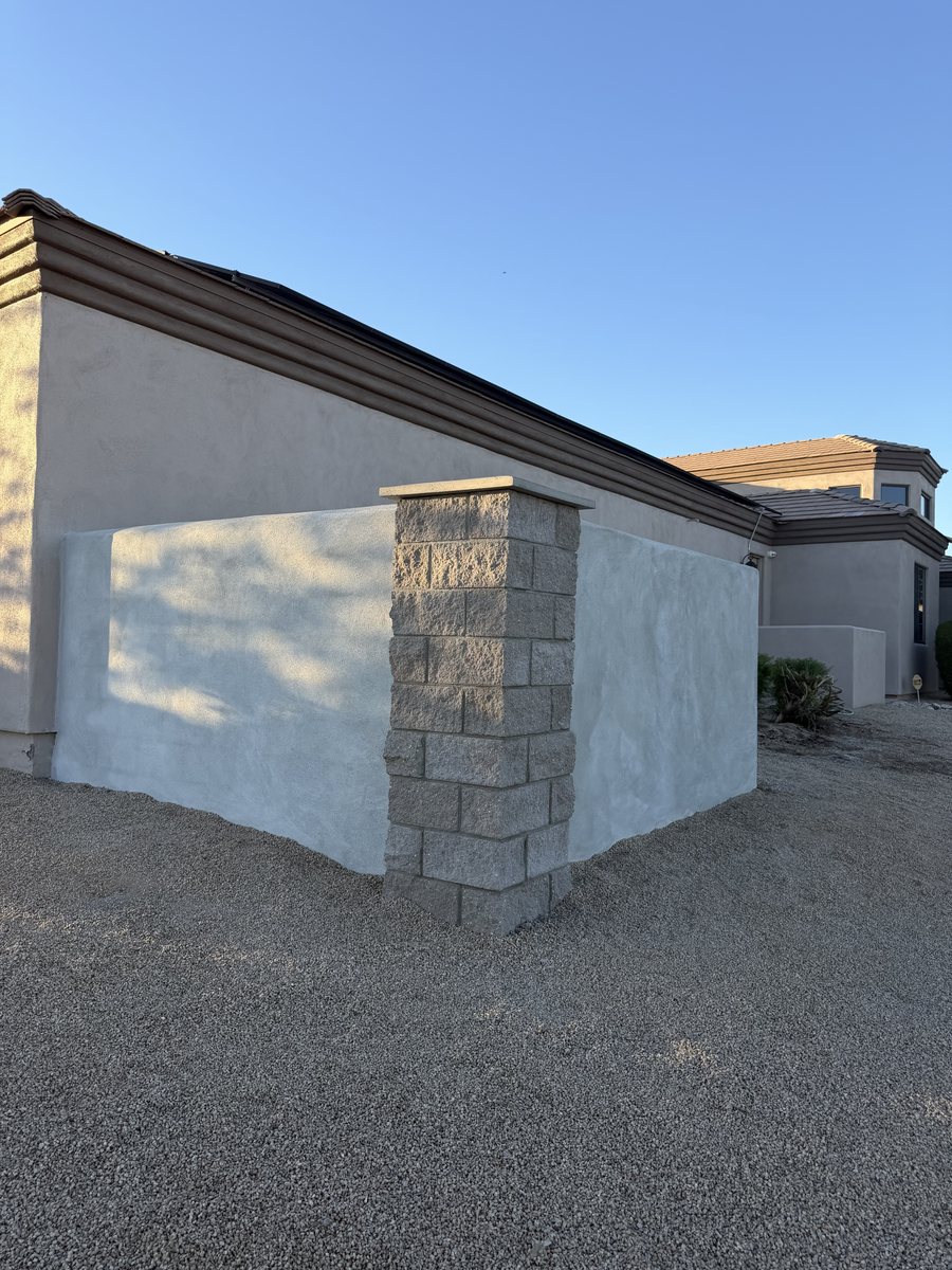 Finished stucco block wall with a split-face block pillar and cap