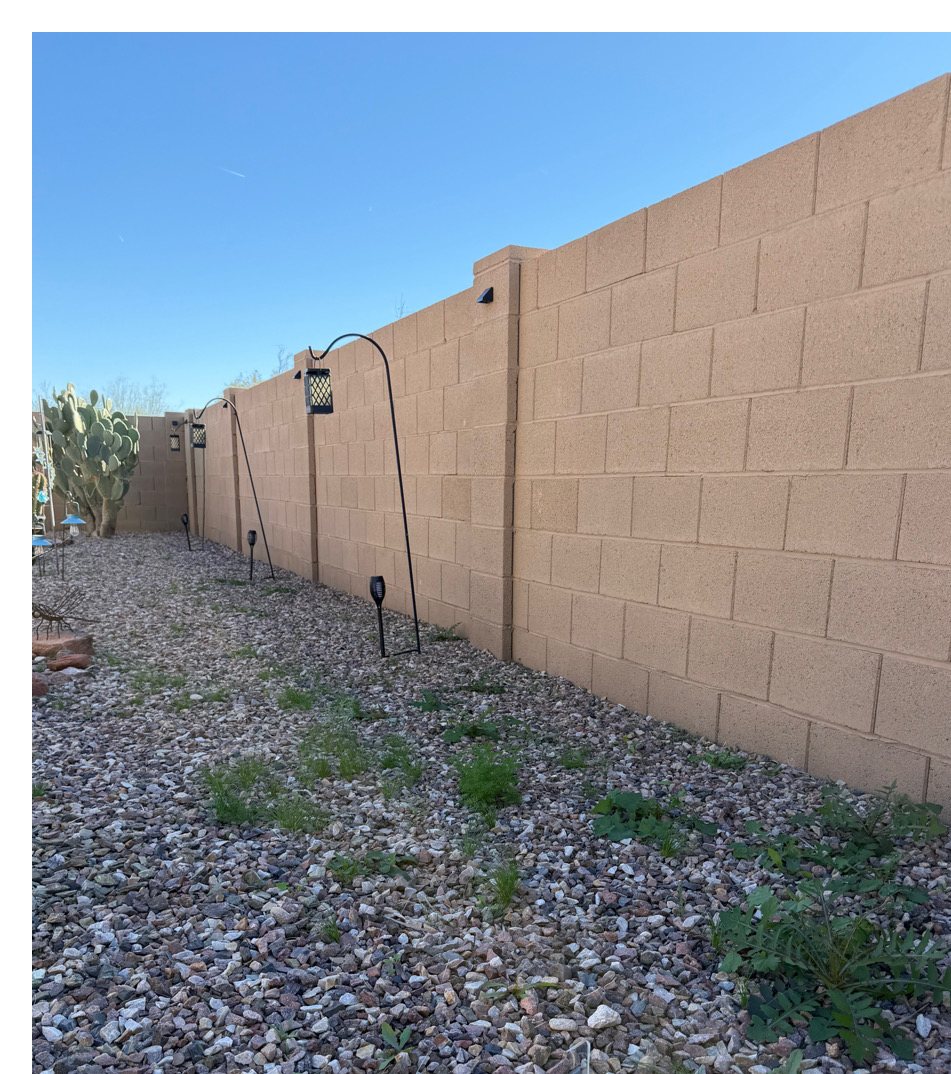 Weeds coming up through decomposed granite along a block wall